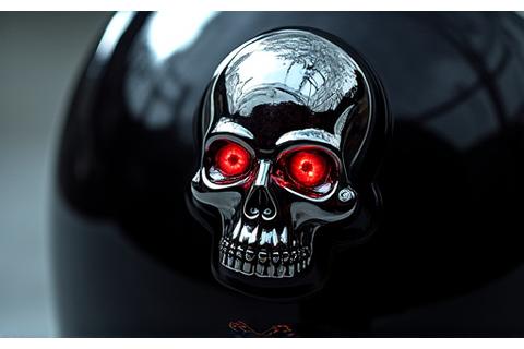 Motorcycle helmet with a stylized chrome skull decal, reflecting light